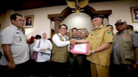 Kepala BNPB Letjen TNI Suharyanto, S.Sos., M.M (kemeja dan rompi hijau), bersama Kepala BMKG Dwikorita Karnawati dan Perwakilan Komisi VIII DPR RI John Kenedy Azis saat memberikan simbolis dukungan bantuan penanganan darurat kepada pemerintah daerah, pada Rapat Koordinasi Penanganan Darurat Bencana Banjir dan Tanah Longsor di Provinsi Sumatera Barat, pada Senin (13/5/2024). (Dok. BNPB)